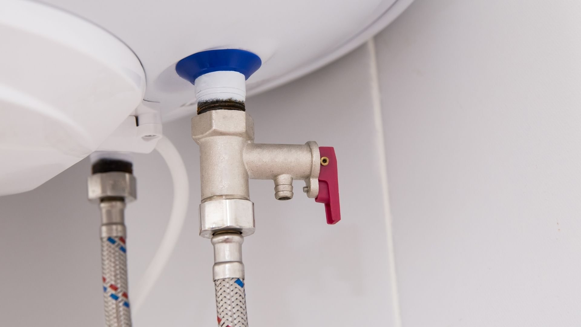 Close-up of plumbing valve with blue handle and red shut-off on ceiling