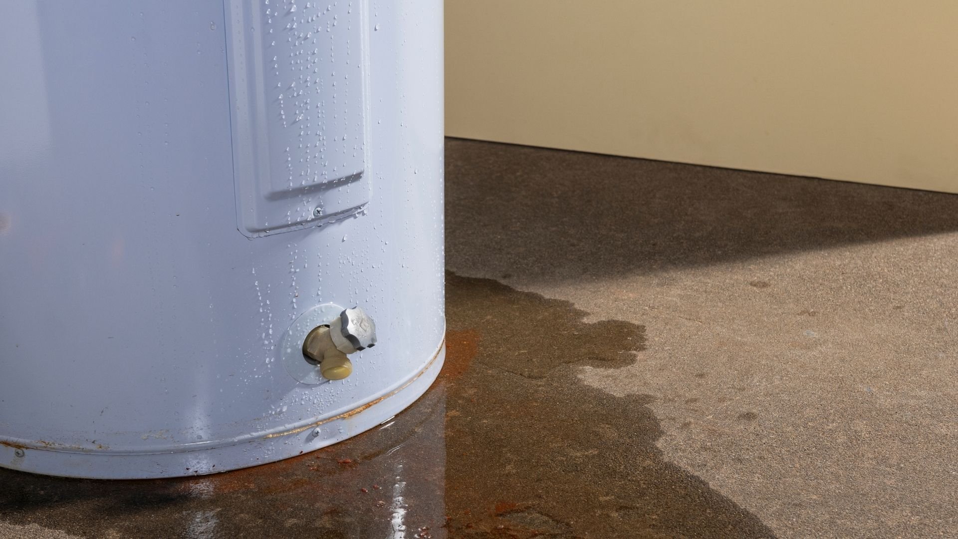 Water heater tank leaking on basement floor creating wet puddle