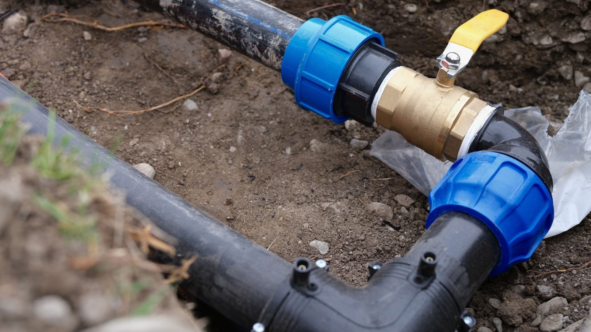 Water pipe valve with blue connectors and yellow handle underground